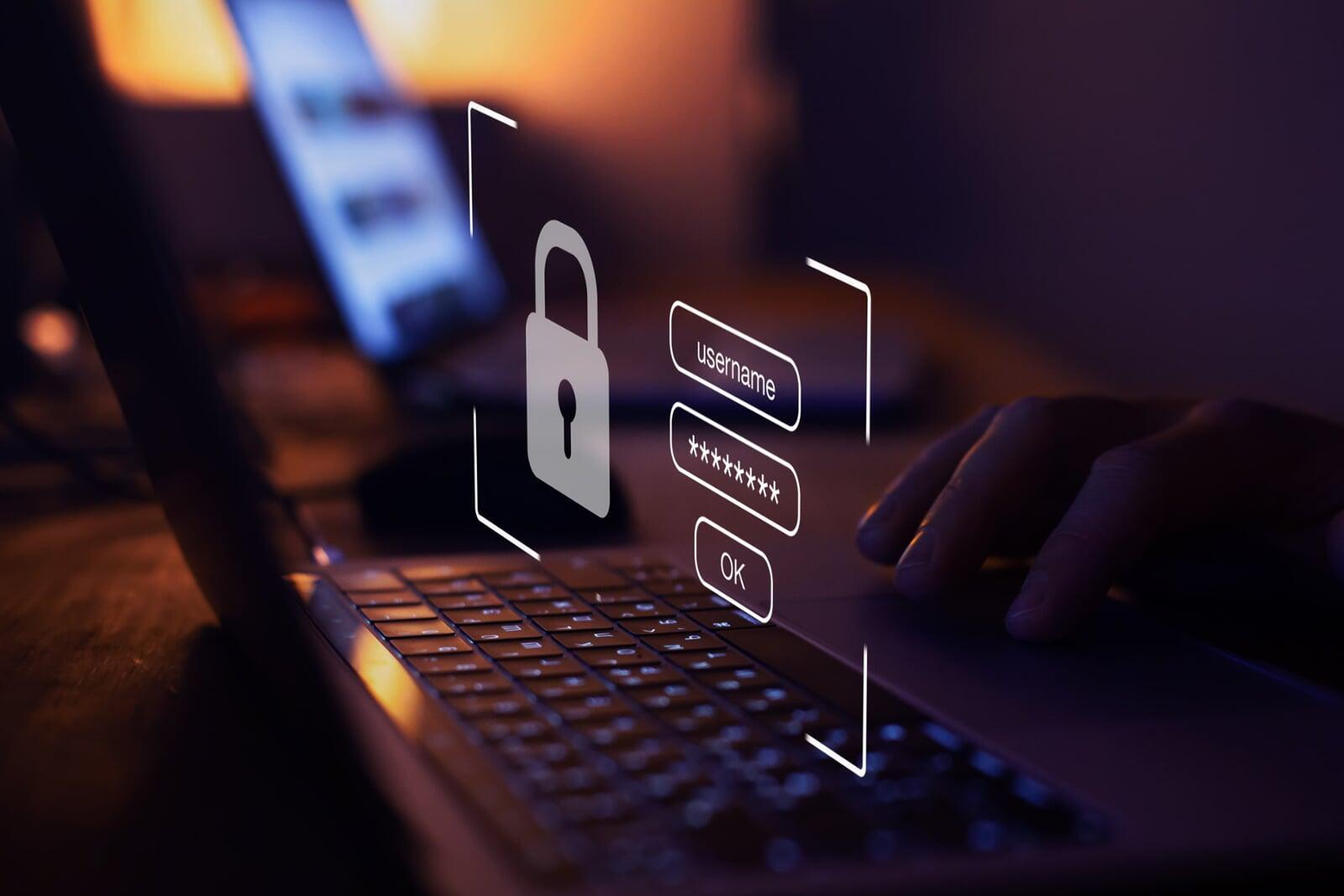 Hands typing on a laptop with a glowing blue digital shield overlay, emphasizing password manager risks and security.