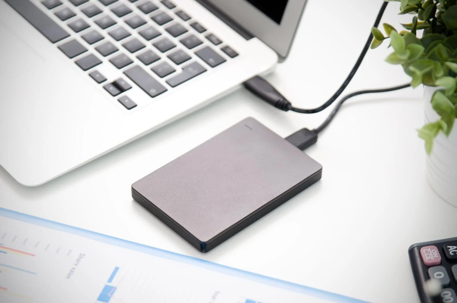 A close-up of an external hard drive connected via USB to a laptop, symbolizing reliable local data protection as part of comprehensive Secure Data Backup Services.