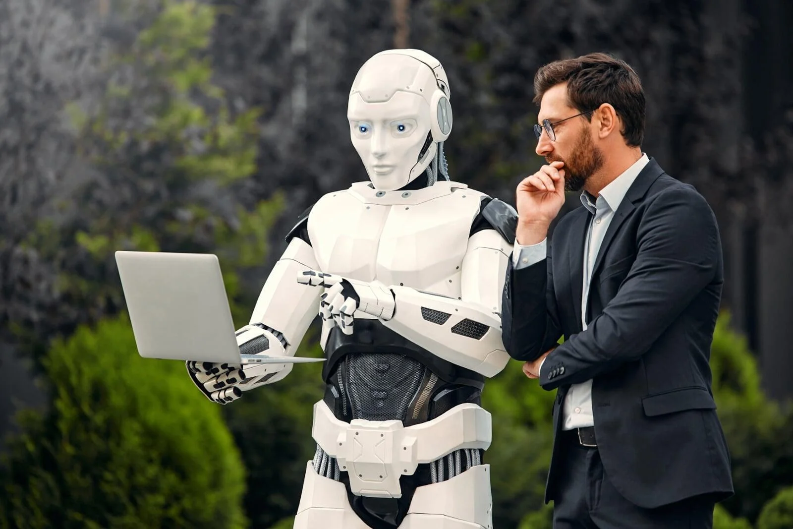 A robot and professional reviewing a laptop, symbolizing the training needed to overcome AI in the workplace challenges.