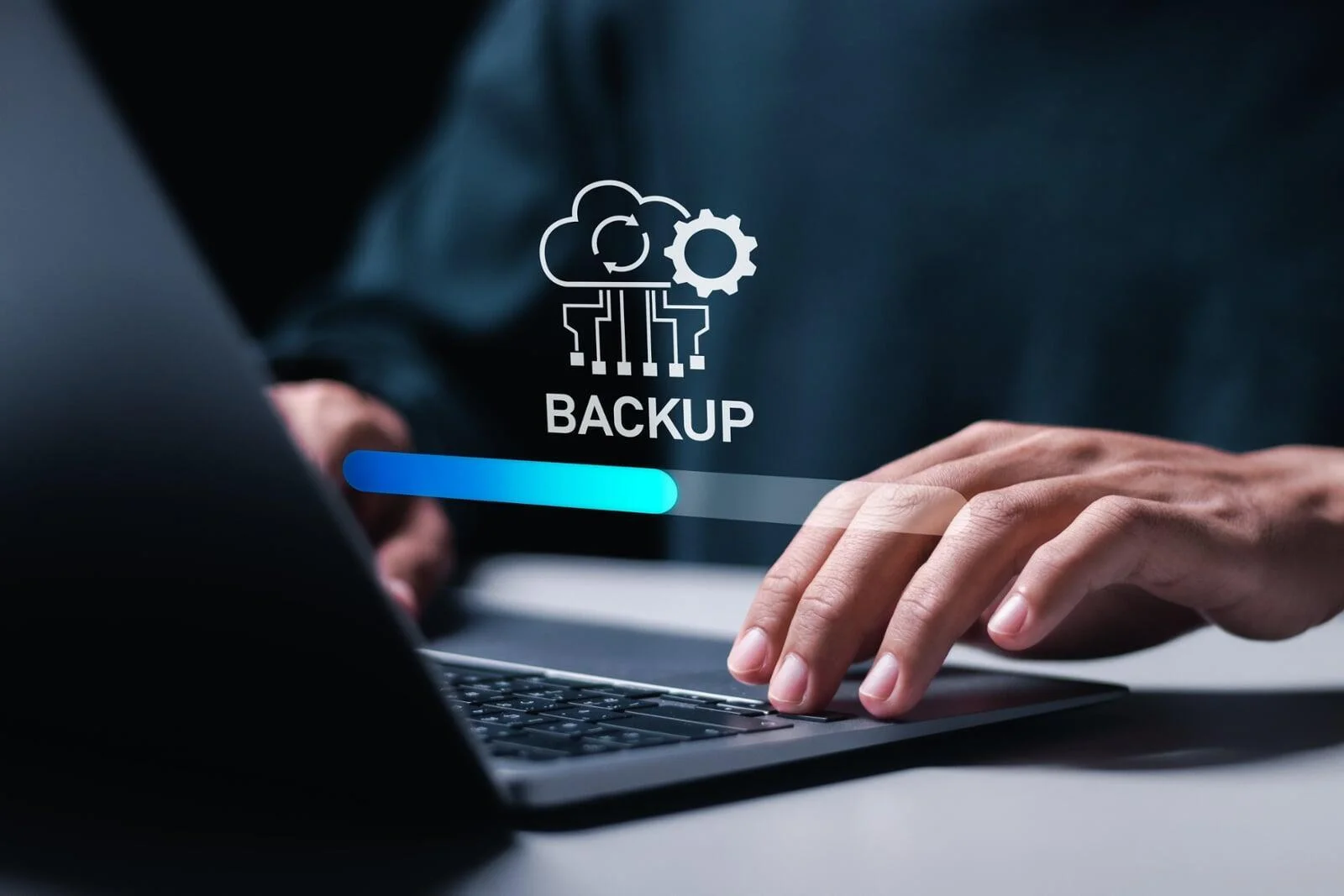 Person typing on laptop with glowing blue backup progress bar and cloud icon.
