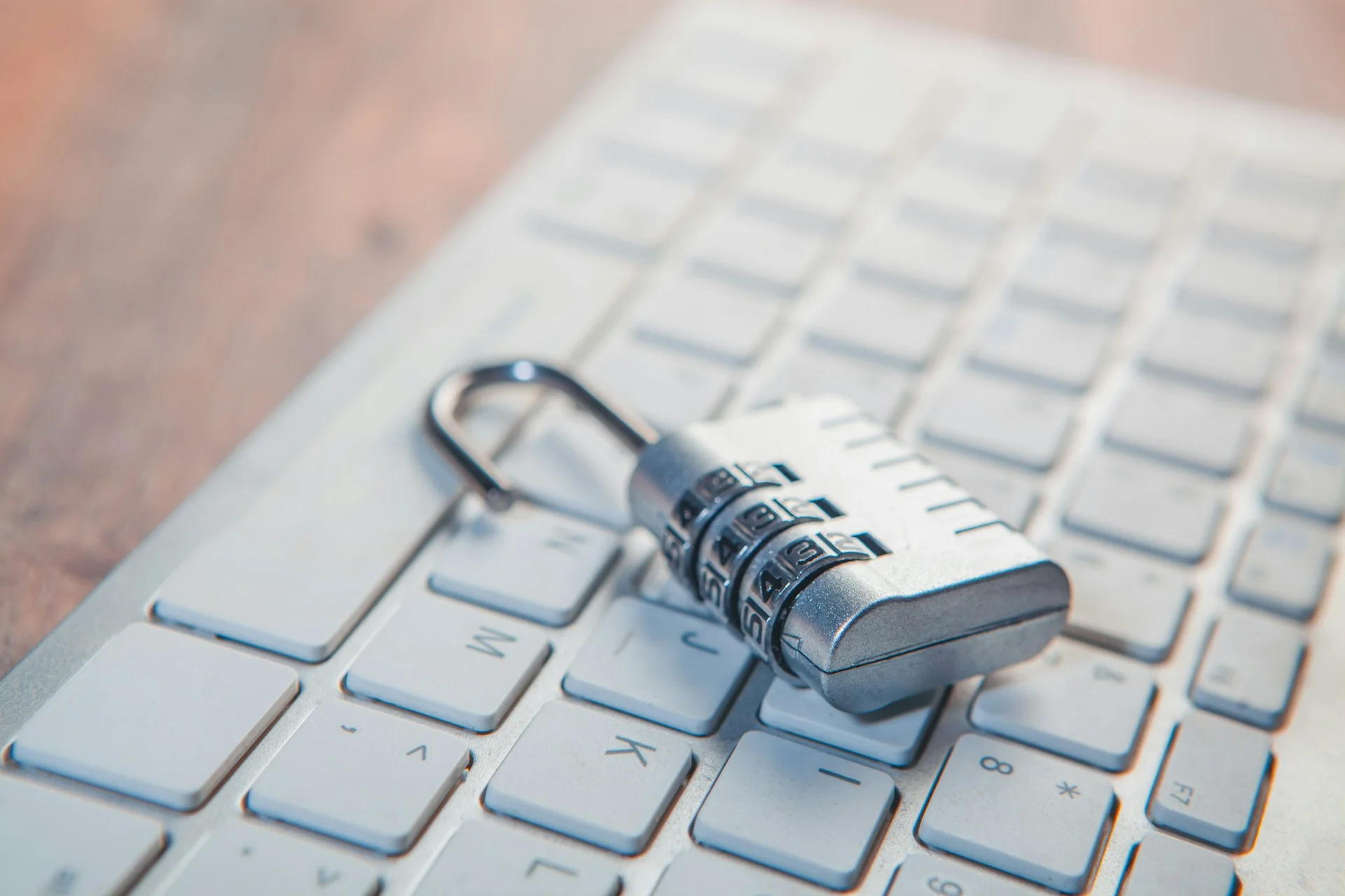 A silver combination padlock sitting open on a white computer keyboard, illustrating the security gaps that a ransomware defense plan aims to close to prevent unauthorized access.