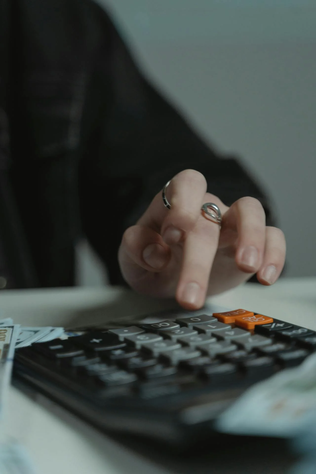 A person using a black calculator next to cash, representing the cost analysis phase of a legacy debt audit IT.