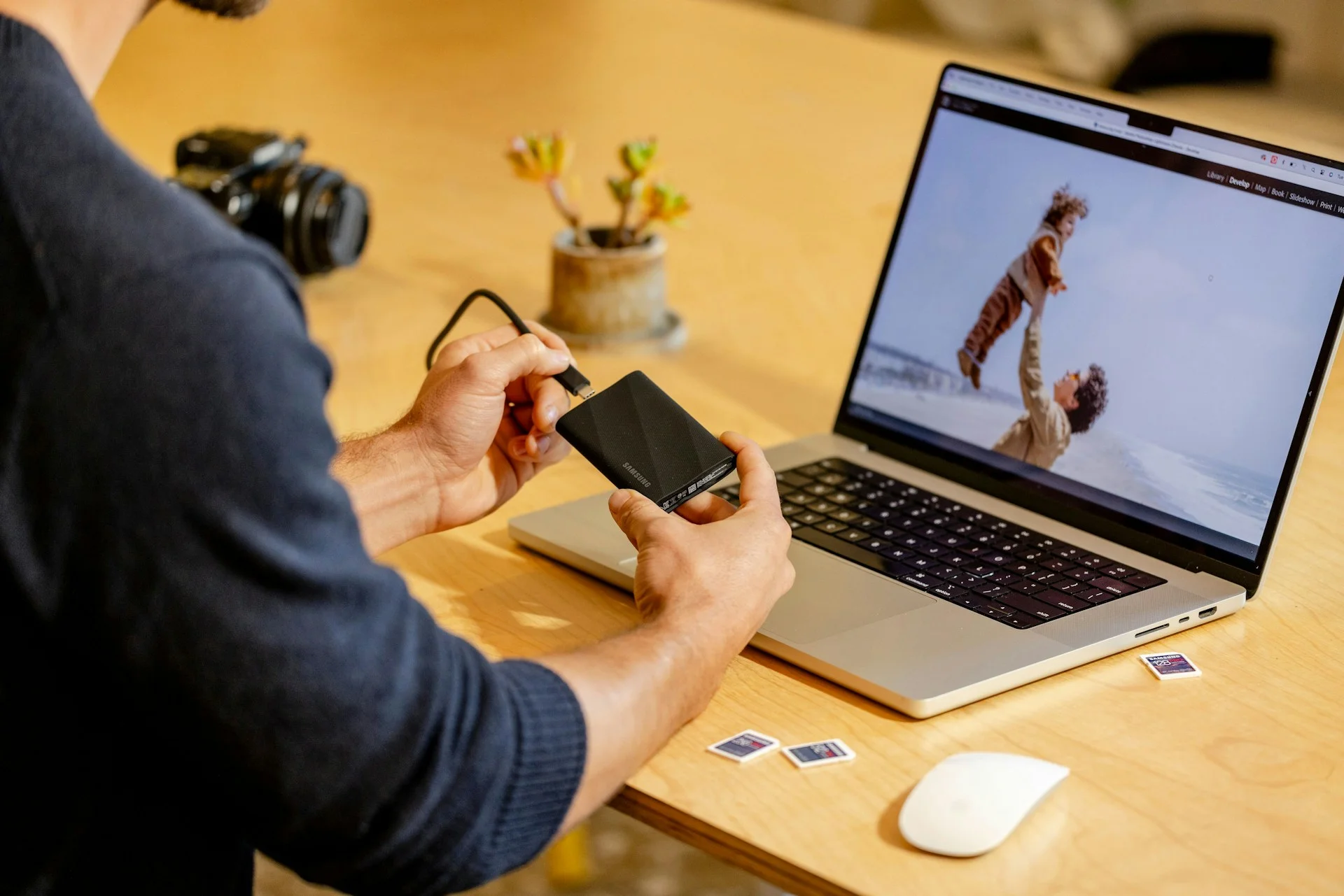 A person connecting a portable SSD to a laptop to move files, representing the local data retrieval phase of a SaaS backup exit strategy.