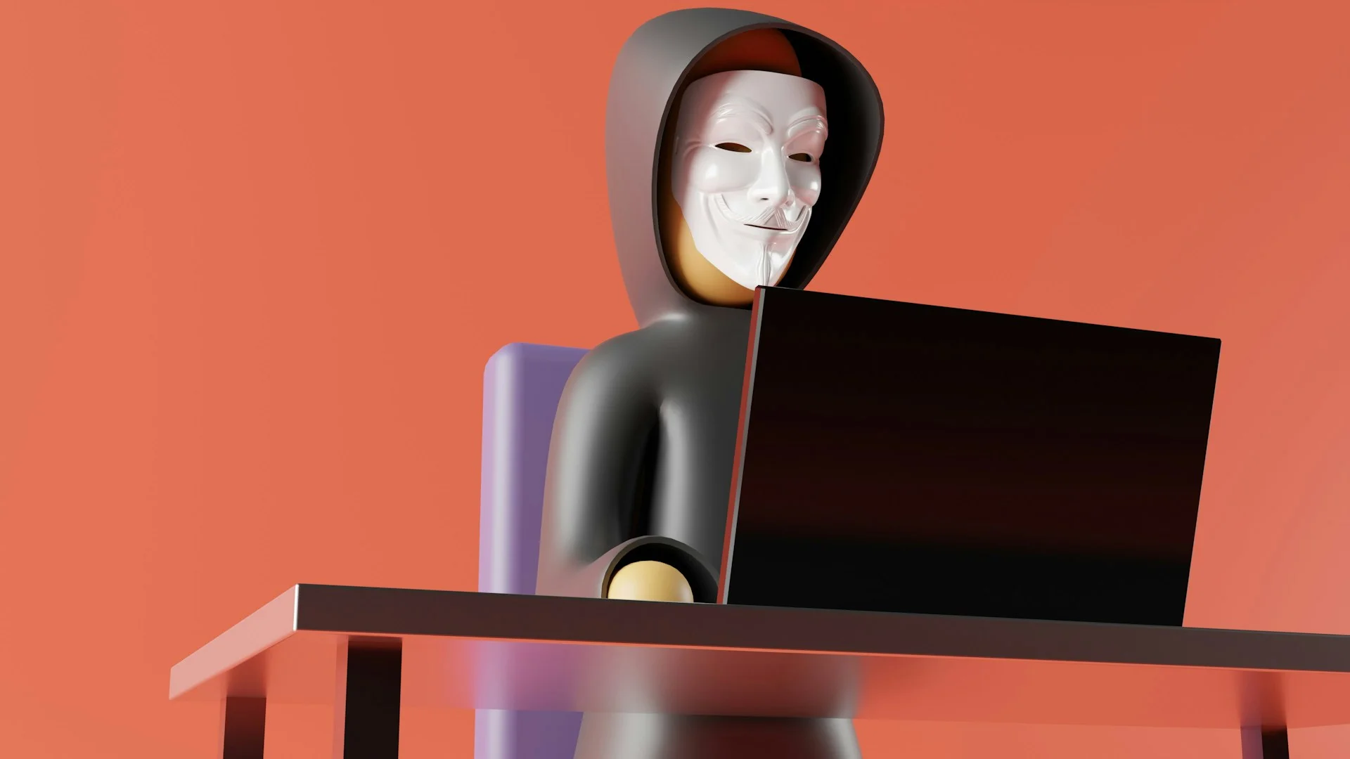 Masked hacker wearing a dark hoodie sitting at a computer desk, illustrating the threat context of what to do in case of a cyberattack.