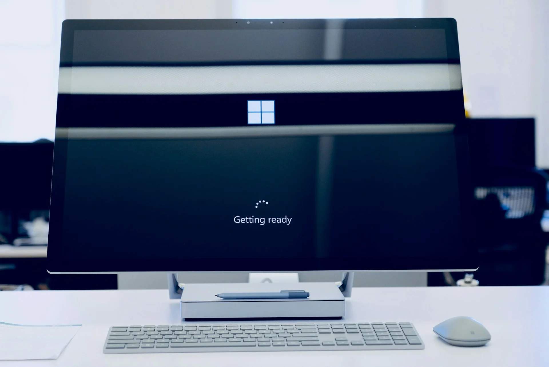 A desktop computer monitor displaying a Windows startup logo and "Getting ready" loading screen, representing system updates and Windows 10 end of support.