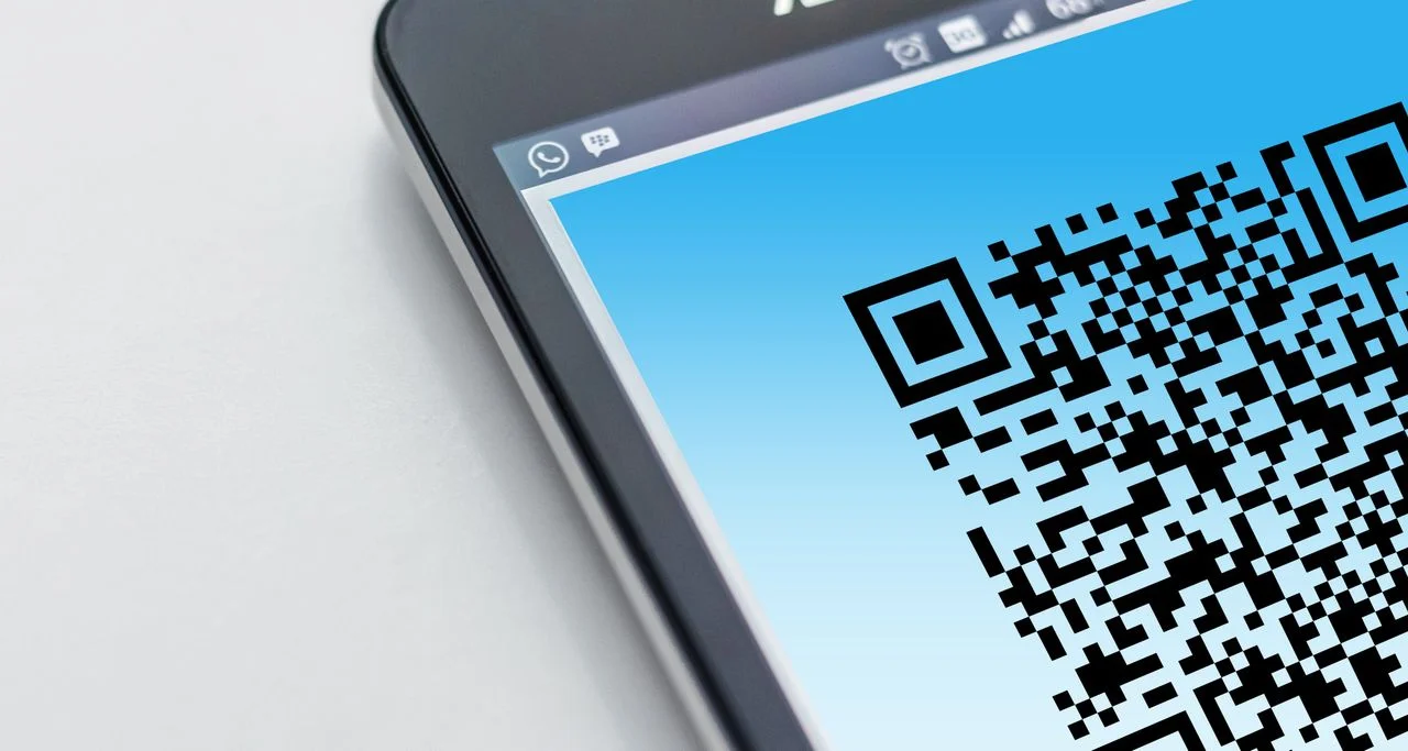 A smartphone screen displaying a large black-and-white QR code, illustrating digital scanning entry points often targeted in QR Code Scams.